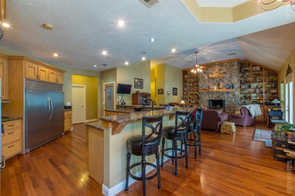 Kitchen bar opening to stone fireplace great room
